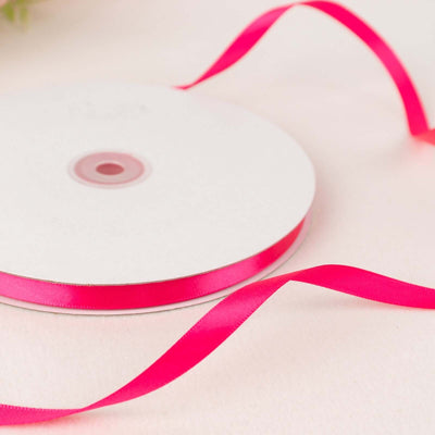 Pink satin ribbon on a spool with a loose strand