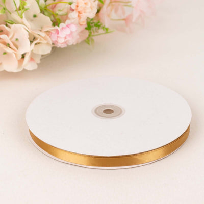 Gold satin ribbon on a spool with floral background