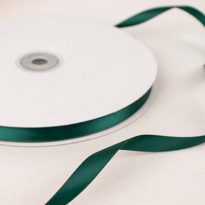 Green satin ribbon on a spool with a loose end.
