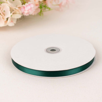 Green satin ribbon on a spool against a soft background.
