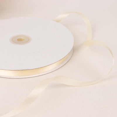 Cream satin ribbon on a spool with a flowing tail