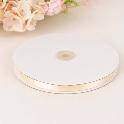 Cream satin ribbon on a spool with floral background.