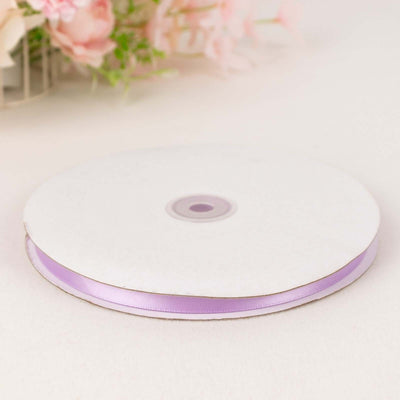 Purple satin ribbon on a white spool against a plain background