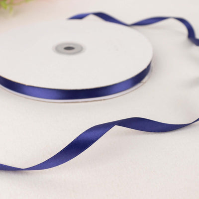 Navy blue satin ribbon on a spool with loose ends