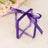 Purple ribbon gift box with flowers on a soft pastel background