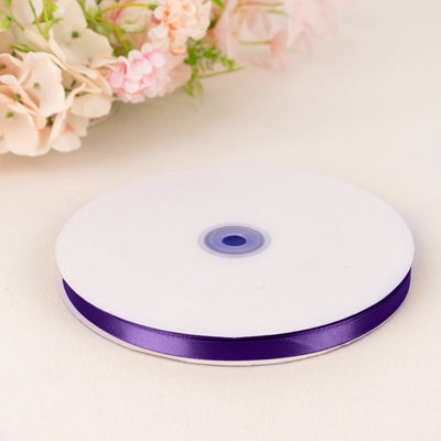 Purple satin ribbon spool on white background with soft pastel flowers