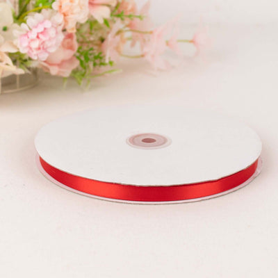Red satin ribbon spool on a plain white background