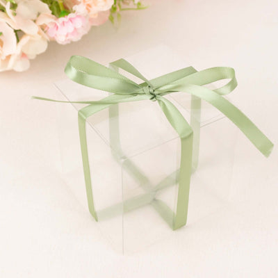 Clear gift box with a green ribbon bow on a plain background.
