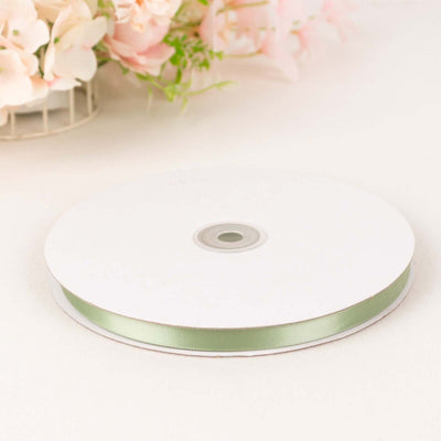 Green satin ribbon on a spool against a plain background