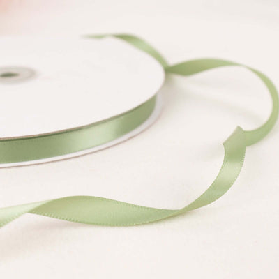 Green satin ribbon on a spool with a loose end curling off.