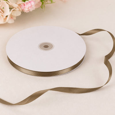 White satin ribbon roll with gold trim on a soft floral background