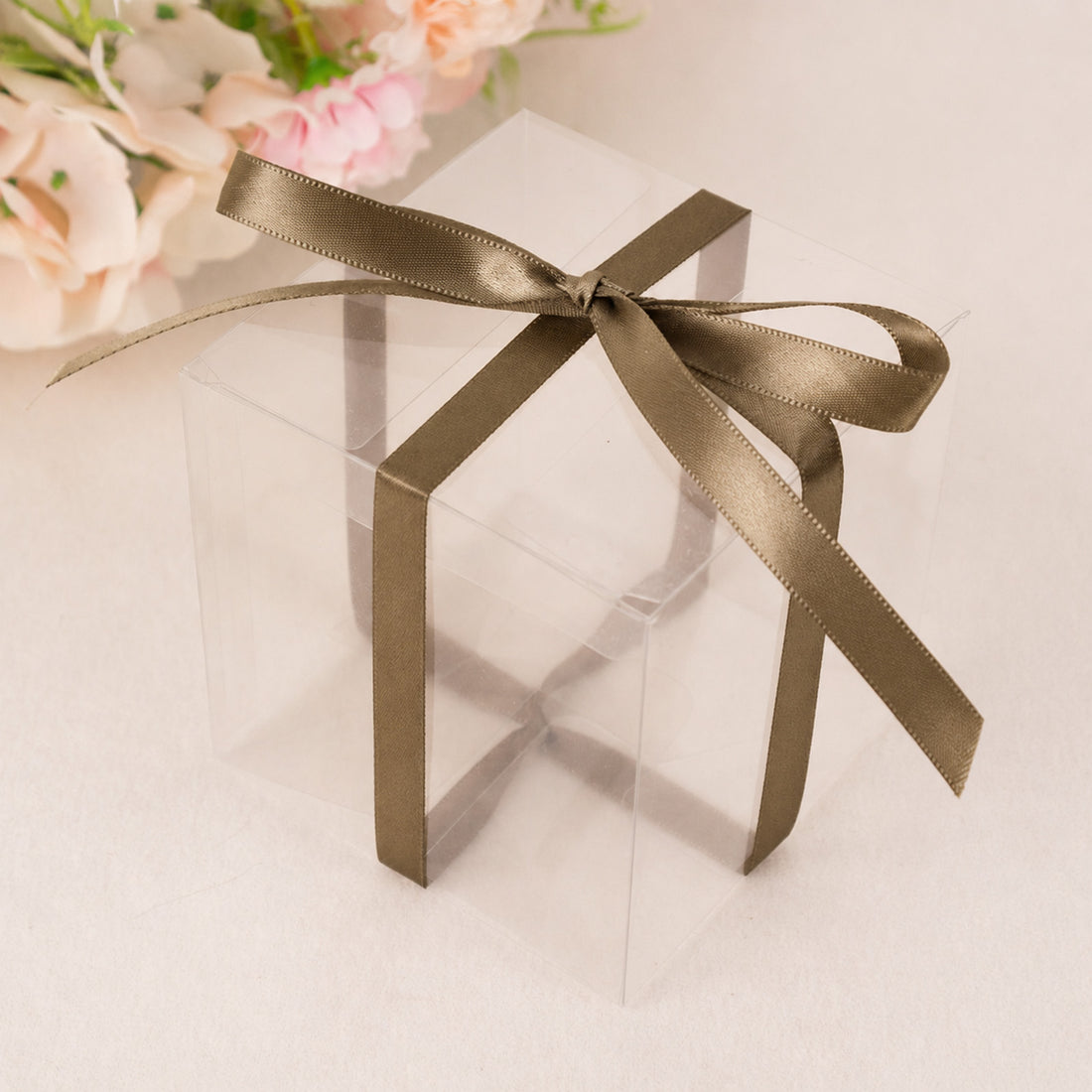 Clear gift box with satin ribbon and floral background