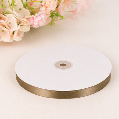 White and gold satin ribbon spool with pastel flowers on a soft background