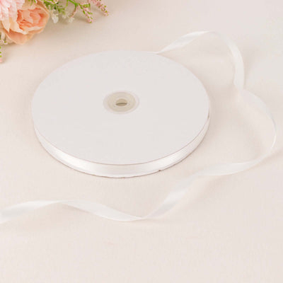 White satin ribbon on a spool with a flowing tail.