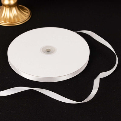 White satin ribbon on a spool with an unspooled length.