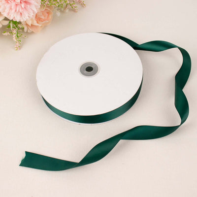 Green satin ribbon on a spool, perfect for crafting and decoration.