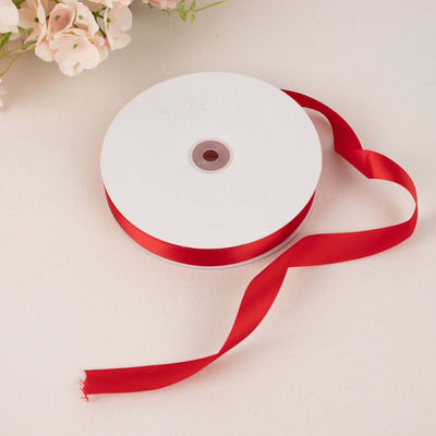 Red satin ribbon on a spool with a flowing tail.
