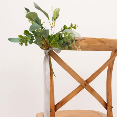 Decorative floral arrangement on a wooden chair with a ribbon.