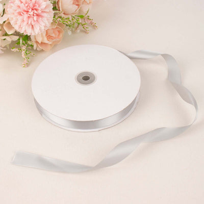 Silver satin ribbon on a spool with floral accents.