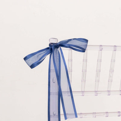 Clear chiavari chair with a blue ribbon bow on the back.