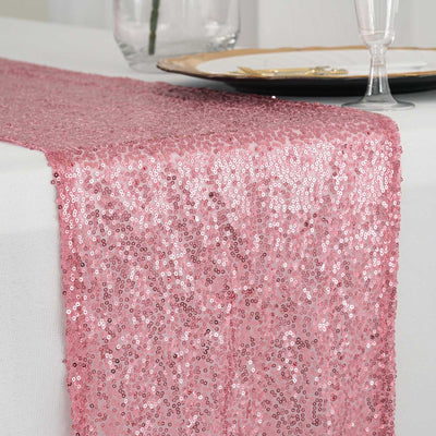 Pink sequin table runner on a white tablecloth.