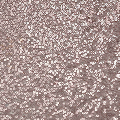 Close-up of sparkling rose gold sequin fabric texture.