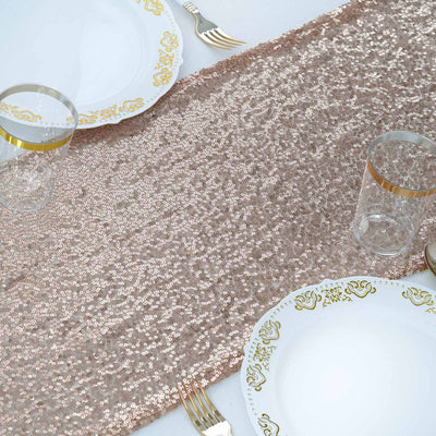 Rose gold sequin table runner on a dining table with elegant plates and glasses.