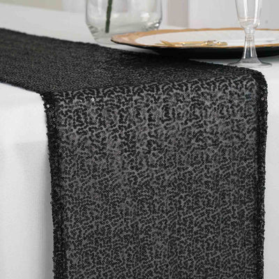 Black sequin table runner on a white table setting.