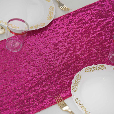 Bright pink sequin table runner on a white table with elegant plates and glassware.