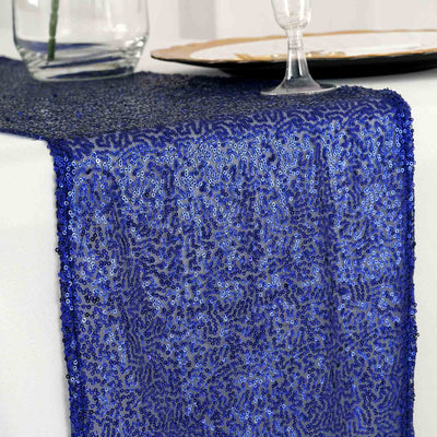 Blue sequin table runner on a dining table with elegant decor.