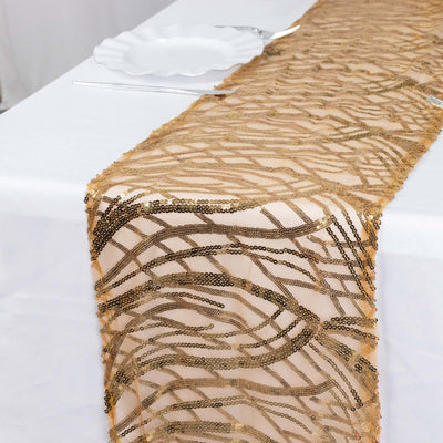 Gold sequined table runner with wavy design on a white tablecloth.