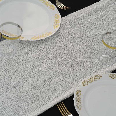 Elegant table setting with white plates and gold accents on a textured table runner.