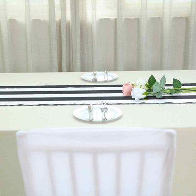 Elegant table setting with black and white striped runner, plates, and fresh flowers.