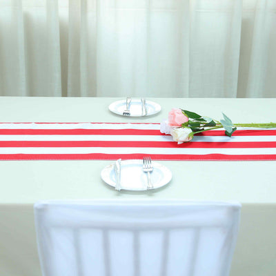 Red and white striped table runner with plates and flowers on a dining table.