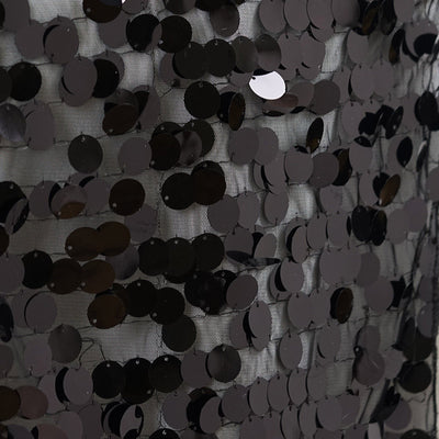 Black sequin fabric with glossy circular embellishments.