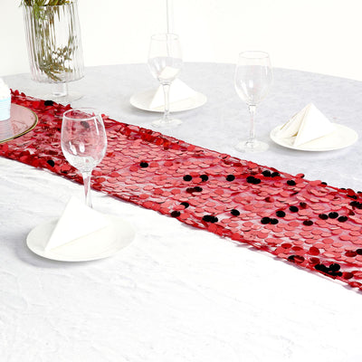 Red sequin table runner on a white table with glassware and napkins.