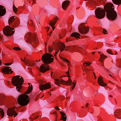 Red sequins scattered on pink fabric background.