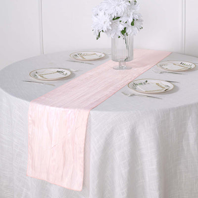 Pink table runner on a round table set with plates and flowers.