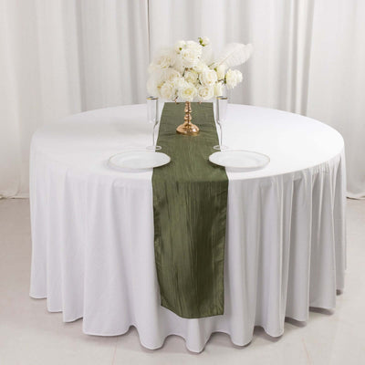 Elegant olive green table runner on a white table with floral centerpiece.