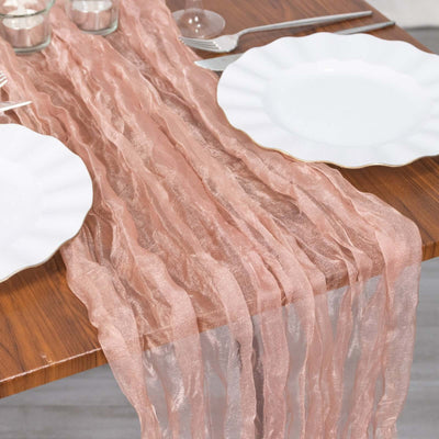 Rose gold table runner on a wooden table with white plates.
