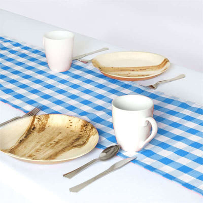 Simple picnic table setting with checkered cloth, plates, mugs, and utensils.