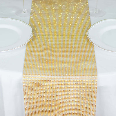 Gold sequin table runner on a white table with plates and glasses.
