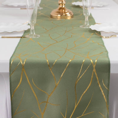 Green table runner with gold leaf design on elegant dining table.