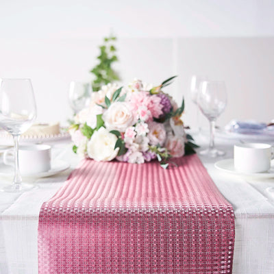 Elegant pink table runner with floral centerpiece on a dining table.