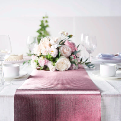 Elegant pink table runner on a festive dining table with floral centerpiece.