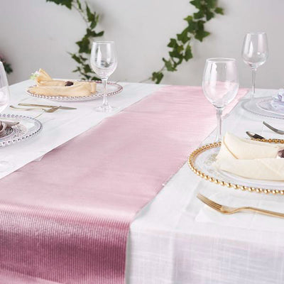 Elegant dining table setting with pink and white table runners, glassware, and cutlery.