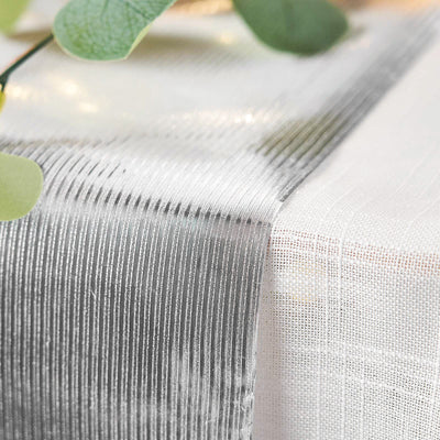 Silver textured table runner with subtle sheen and greenery accents.