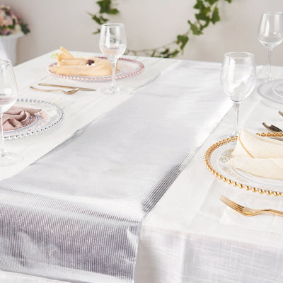 Elegant dining table setup with silver and white table runner and decorative plates.