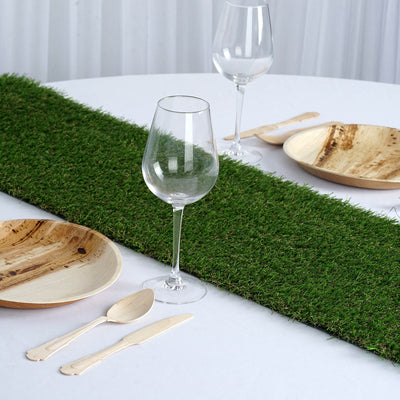 Table setting with grass runner, wooden plates, and glassware.