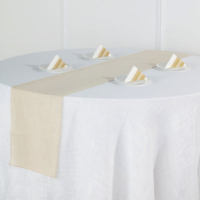 Beige table runner on a round table with plates and folded napkins.